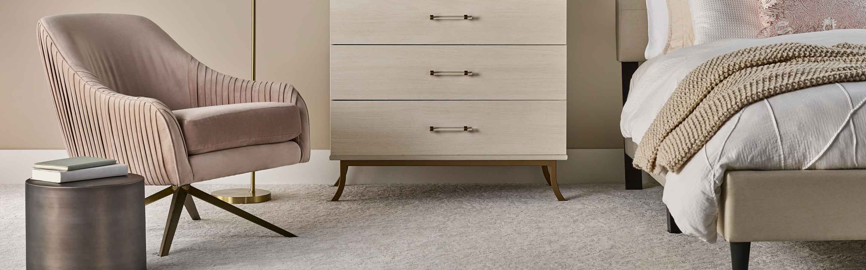 textured carpet in modern bedroom with blush pink and red accents, layered bedding and pink armchair